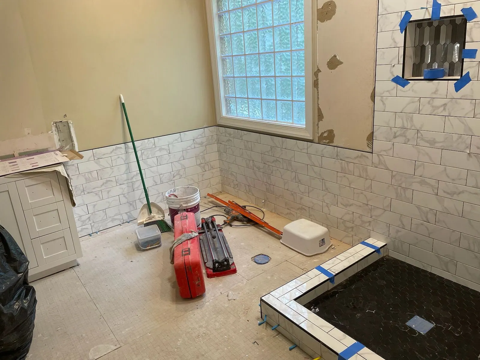 Tile wainscot and tub surround being set during a bathroom remodel
