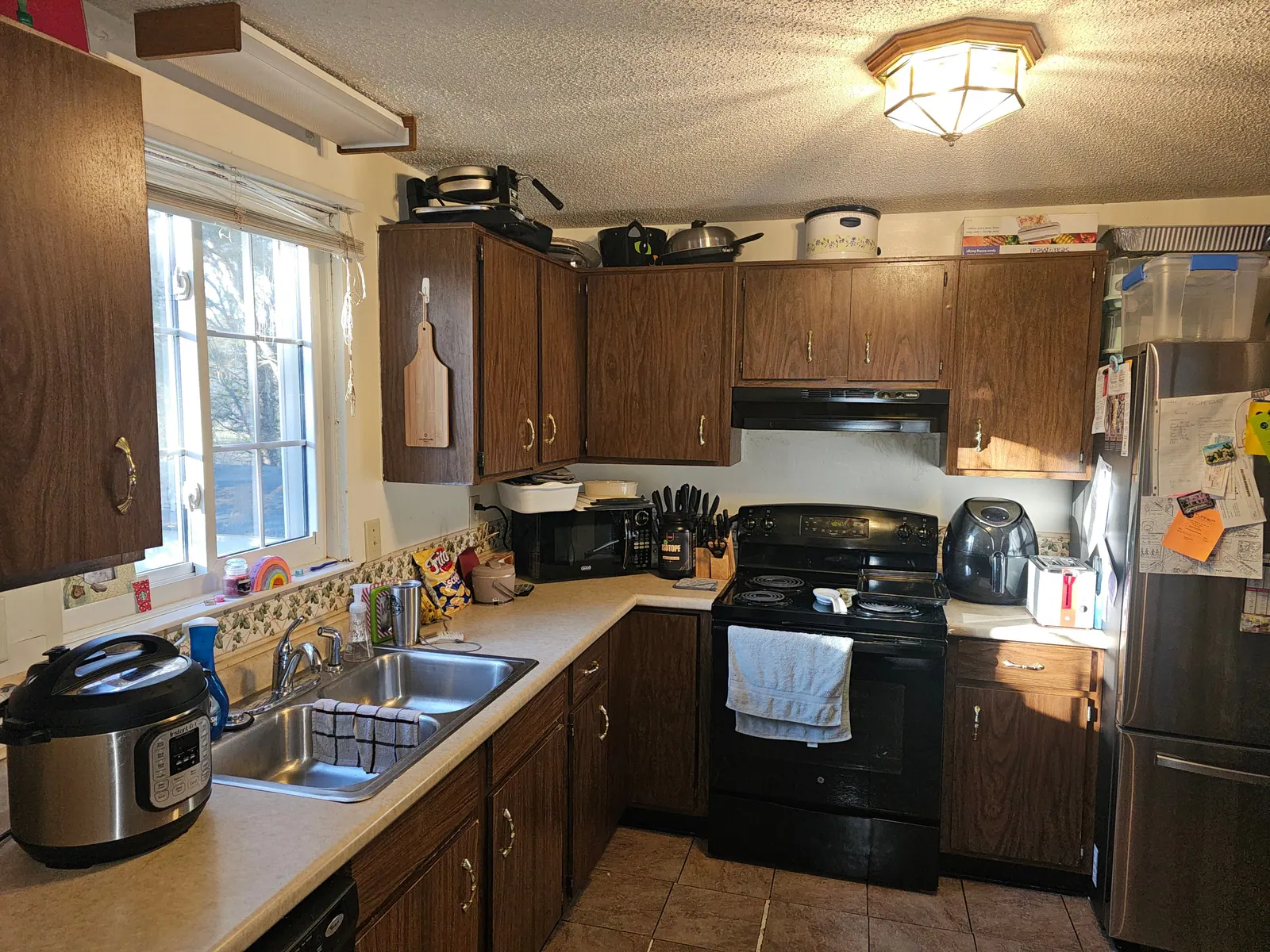 Kitchen before a remodel with dark wood cabinets and laminate counters