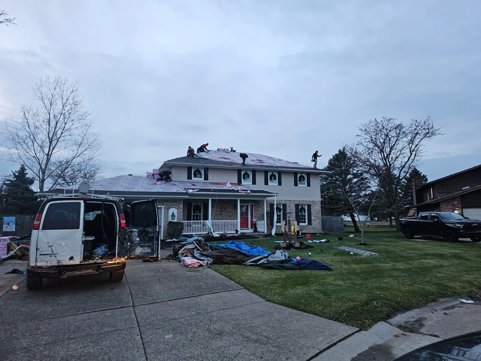 Roof replacement in progress on a two-story colonial with the crew on the roof