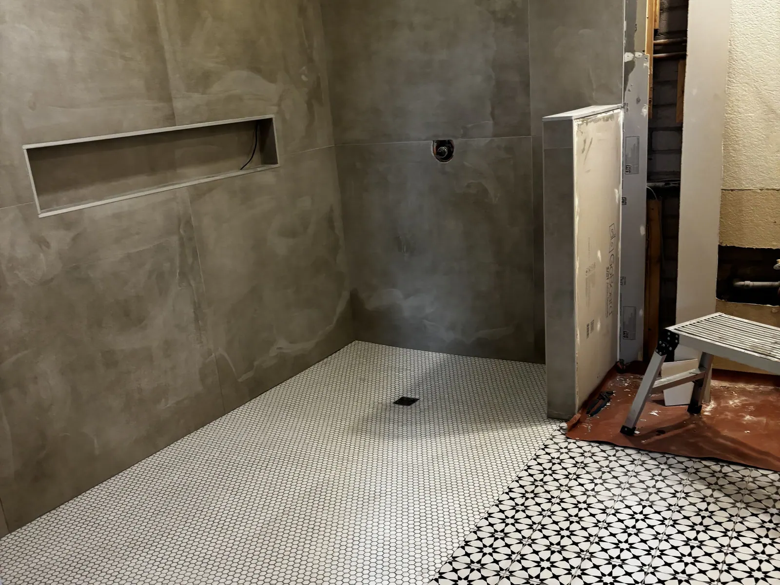Shower walls prepped with a long niche above a new mosaic floor
